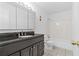 Bathroom featuring a dark vanity with a black countertop, white tile and updated fixtures at 1301 Cumberland Se Ct, Smyrna, GA 30080