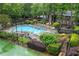 An in-ground pool surrounded by ample seating, lush trees, landscaping, and a tennis court at 1301 Cumberland Se Ct, Smyrna, GA 30080