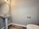 Cozy powder room features a pedestal sink, round mirror, and wood-look flooring at 2526 Piering Dr, Lithonia, GA 30038