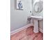 Stylish powder room featuring a pedestal sink and elegant wall art above hardwood floors at 5605 Waters Edge Trl, Roswell, GA 30075