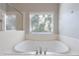 Bathroom featuring a large soaking tub under a window, complemented by a glass-enclosed shower at 2687 Mountain Oaks Ct, Powder Springs, GA 30127