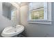 Powder room featuring a pedestal sink, decorative mirror, and natural lighting at 2687 Mountain Oaks Ct, Powder Springs, GA 30127