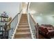 Carpeted staircase with dark wood railing leading to a living area with leather sofa at 4750 Sabino Bnd, Cumming, GA 30040