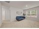This bonus room features a blue sofa, neutral walls, and natural light from the windows overlooking the neighborhood at 4827 Golden Finch Ln, Powder Springs, GA 30127