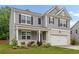 Two-story home with gray siding, brick accents, two-car garage, and well-manicured landscaping at 4827 Golden Finch Ln, Powder Springs, GA 30127
