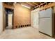 Unfinished basement area with exposed beams, painted walls, and a white refrigerator near the door at 5215 Tealing Ne Dr, Roswell, GA 30075