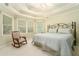 Inviting bedroom with tray ceiling, rocking chair, and large windows at 5215 Tealing Ne Dr, Roswell, GA 30075