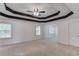 Spacious primary bedroom with tray ceiling, fan, and neutral carpet; features two windows for natural light at 2725 Sedgeview Way, Buford, GA 30519