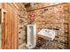 Rustic bathroom with urinal, sink, wood door and brick wall at 527 Main St, Suwanee, GA 30024
