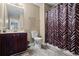 A bathroom with neutral walls, a dark vanity, toilet, and a shower tub with a patterned curtain at 7328 Vigo Dr, Lithonia, GA 30058