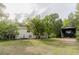 Backyard view with large lawn and carport showcases ample space for parking and outdoor activities at 8315 Nicholson Rd, Cumming, GA 30028
