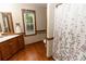 Well-lit bathroom with wood floors, vanity, framed mirror, and shower with decorative curtain at 8315 Nicholson Rd, Cumming, GA 30028