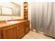 Cozy bathroom featuring wood floors, vanity, and shower with decorative shelving unit at 8315 Nicholson Rd, Cumming, GA 30028