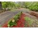 Gravel driveway lined with landscaping, leading to a wooded area, gives a rustic, natural feel at 8315 Nicholson Rd, Cumming, GA 30028