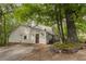 View of the home's exterior, featuring stone accents and a gravel driveway, set among mature trees at 8315 Nicholson Rd, Cumming, GA 30028