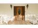 Charming porch with inviting seating flanking a gorgeous wooden front door and decorative sconces at 8315 Nicholson Rd, Cumming, GA 30028