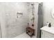 Elegant tiled shower featuring marble walls, modern fixtures, a built-in shelf and a comfortable seating area at 8315 Nicholson Rd, Cumming, GA 30028