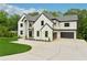 Stunning two-story home with white brick, black trim, a large driveway, and mature landscaping at 2977 N Bogan Rd, Buford, GA 30519