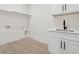 This bright laundry room features white cabinets, a sink, and modern fixtures at 2977 N Bogan Rd, Buford, GA 30519