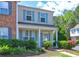 Exterior elevation of the townhome featuring a covered front porch and landscaped front yard at 10900 Wittenridge Dr # L6, Alpharetta, GA 30022