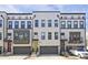 Charming townhome exterior featuring gray garages, a yellow front door, and red door with traditional brick and siding at 1149 Ansel Nw Ln, Atlanta, GA 30318