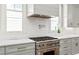 Close-up of the gourmet kitchen with a stainless steel range and hood, white cabinets, and quartz countertops at 259 Sisson Ne Ave, Atlanta, GA 30317