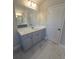 Bathroom featuring marble-look tile flooring, a grey vanity, and a large mirror with updated lighting fixtures at 1107 Kingston Hill Dr, Loganville, GA 30052