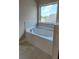 Large tub with tile surround features a view to the yard at 1107 Kingston Hill Dr, Loganville, GA 30052