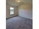 Cozy bedroom with neutral carpet, trim, and a window showcasing the outdoor view at 1107 Kingston Hill Dr, Loganville, GA 30052