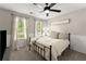 Cozy bedroom featuring a ceiling fan, soft carpet, and sign that says, 
