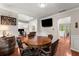 A modern dining room featuring a round wooden table, a flat screen TV, a decorative barrel, and hardwood flooring at 6520 Glen Pond Trce, Cumming, GA 30028