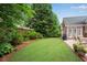 Beautiful backyard showcasing lush green lawn, mature trees, mulched flower beds, and a patio with outdoor furniture at 350 Declaire Ne Way, Marietta, GA 30067