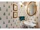 Charming powder room features patterned wallpaper, gold accents, a pedestal sink, and unique decor at 350 Declaire Ne Way, Marietta, GA 30067