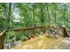 Outdoor deck with wooden flooring and railing, and lounge seating surrounded by trees at 2261 Ravenwood Trl, Marietta, GA 30066