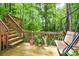 Wooden deck features stairs, swing and railing surrounded by lush trees, ideal for relaxing in a serene backyard at 2261 Ravenwood Trl, Marietta, GA 30066