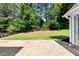 Brick patio leads to expansive, lush backyard surrounded by mature trees and hedges with metal fence at 960 River Valley Dr, Dacula, GA 30019