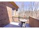 Brick balcony with metal railing, a table, and potted flowers offers a view of the bare winter trees at 120 Kettering Trce, Tyrone, GA 30290