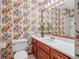 Bathroom featuring wood cabinets, floral wallpaper, and mirror at 497 Fire Fly Dr, Tucker, GA 30084
