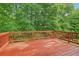 View of spacious red-stained wooden deck surrounded by lush greenery at 497 Fire Fly Dr, Tucker, GA 30084