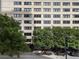 Mid-rise brick apartment building with lush green trees in front and street-level shops at 878 Peachtree St # 601, Atlanta, GA 30309