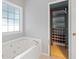 Bathroom with a tub, large window, and closet with shelving at 1645 Four Notch Rd, Carrollton, GA 30116