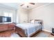Cozy bedroom with hardwood floors, ceiling fan, closet, dresser, and plush queen bed with decorative pillows at 4090 Cooks Farm Nw Dr, Kennesaw, GA 30152