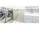 Bright laundry room featuring front load washer and dryer set, gray cabinets, and patterned tile flooring at 4090 Cooks Farm Nw Dr, Kennesaw, GA 30152