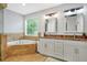 Elegant bathroom featuring a soaking tub, double vanity with granite countertops, and ample natural light at 4125 Fallbrook Dr, Duluth, GA 30096