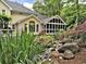 Back of home features a sunroom, screened in porch, deck, and a tranquil water feature in landscaped backyard at 5625 Brookstone Nw Dr, Acworth, GA 30101
