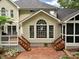 Tan home exterior showcasing a brick patio with wooden stairs leading to a deck and large arched window at 5625 Brookstone Nw Dr, Acworth, GA 30101