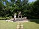 Secluded backyard retreat featuring an outdoor stone fireplace with a seating area and lush greenery at 1205 Renaissance Se Ct, Mableton, GA 30126