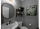 Stylish powder room featuring a unique mirror, dark fixtures, and decorative shelving and artwork at 1205 Renaissance Se Ct, Mableton, GA 30126