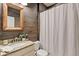 Rustic bathroom featuring wood accent wall, granite countertop, decorative mirror and tub with white shower curtain at 134 Johnston Farm Ln, Woodstock, GA 30188