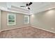 Bedroom with a tray ceiling, fan, carpeted floor, and two windows overlooking green space at 134 Johnston Farm Ln, Woodstock, GA 30188